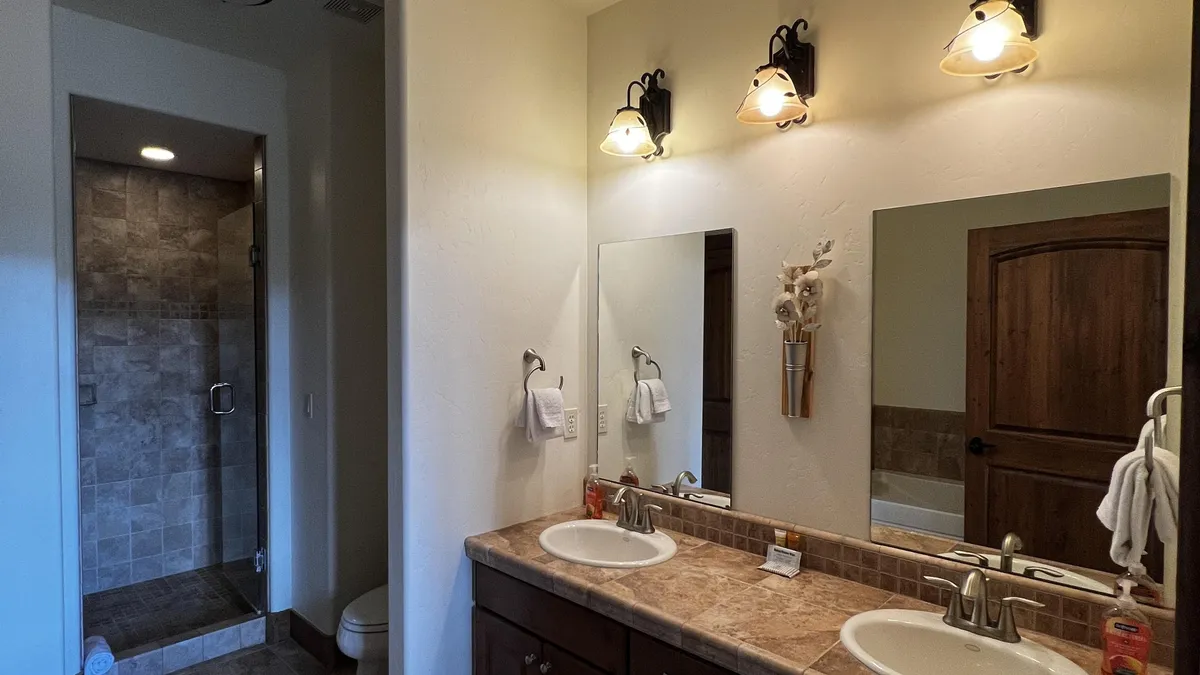 A bright, organized bathroom features a double sink vanity with large framed mirrors and a shower area, creating an inviting environment for morning rituals or evening unwinding.