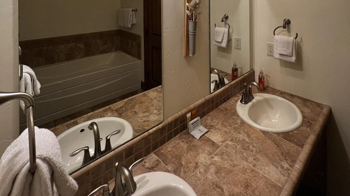 A luxurious bathroom featuring a spacious bathtub, elegant sink with mirrors, plush towels, and soft lighting. The soothing environment creates the perfect spot for unwinding after a day of adventure.