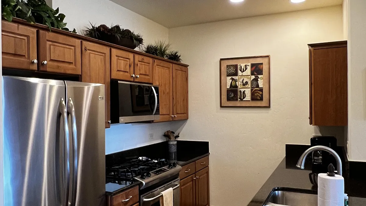 This image captures a stylish and functional kitchen space featuring dark granite countertops, high-end stainless steel appliances, wooden cabinetry, and vibrant wall art. The layout is open and inviting, perfect for preparing meals and entertaining guests.